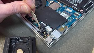 image of epoxy glue being applied to remount laptop hinge screw bushes