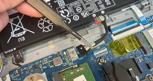 image of tweezers being used to disconnect the battery inside a laptop